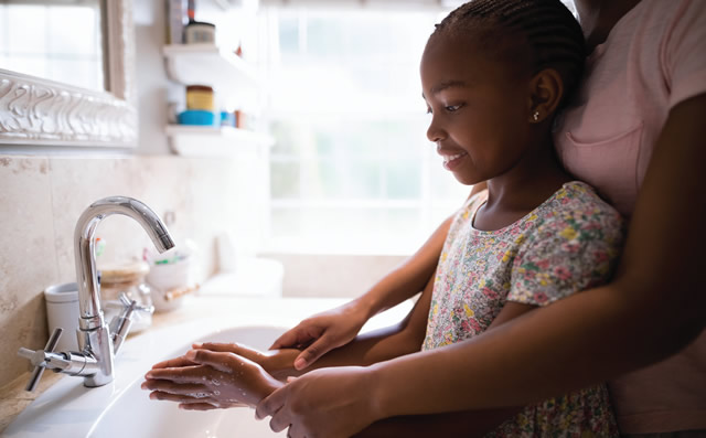 adult helping child wash their hands